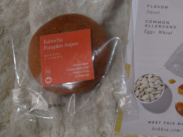 A wrapped pumpkin and white bean paste cake next to a leaflet describing it