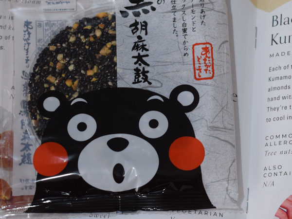 A wrapped black sesame seed snack cake next to a leaflet describing it