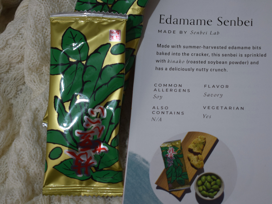 Two packed of baked edamame crackers next to a leaflet describing them