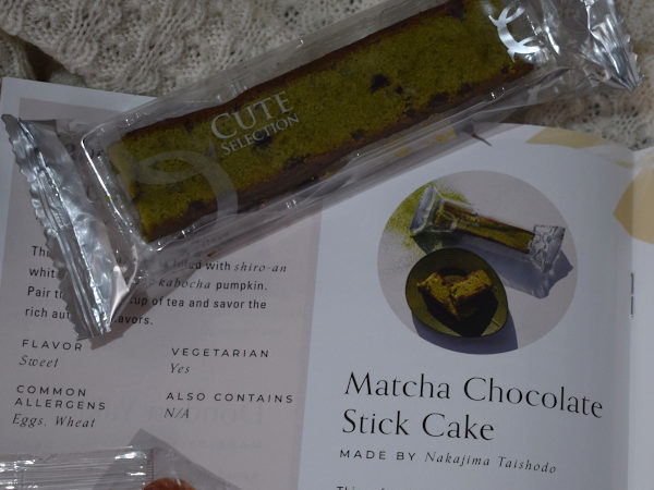 A wrapped matcha green tea and dark chocolate cake slice next to a leaflet describing it
