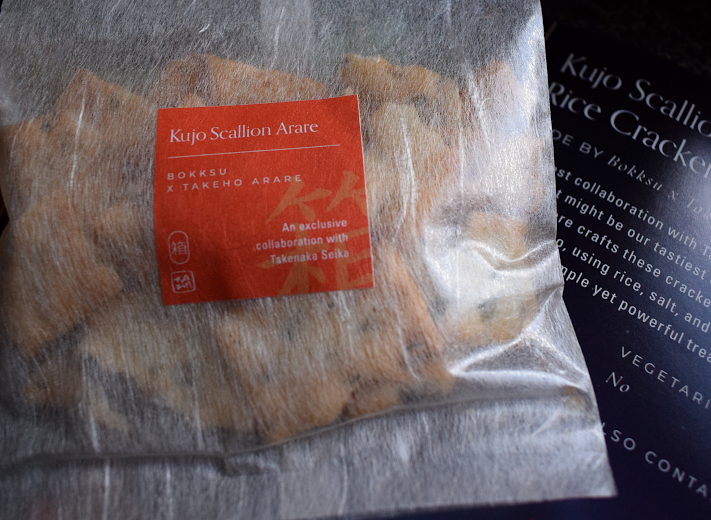 a packet of scallion rice crackers next to a leaflet describing them