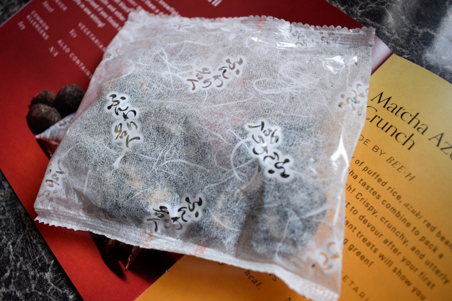 a packet of dried black sesame flavoured mochi next to a leaflet describing them