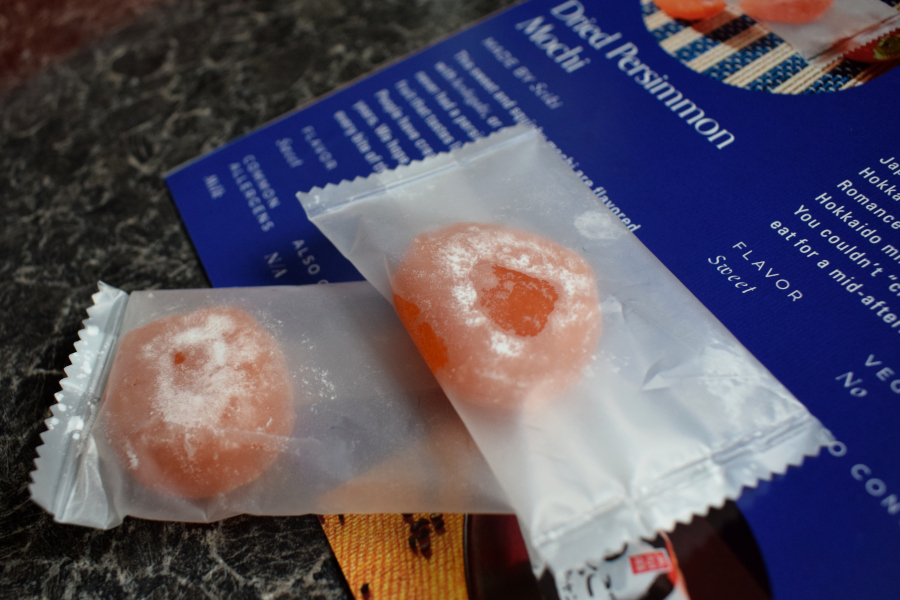 two individually wrapped persimmon flavoured mochi next to a leaflet describing them