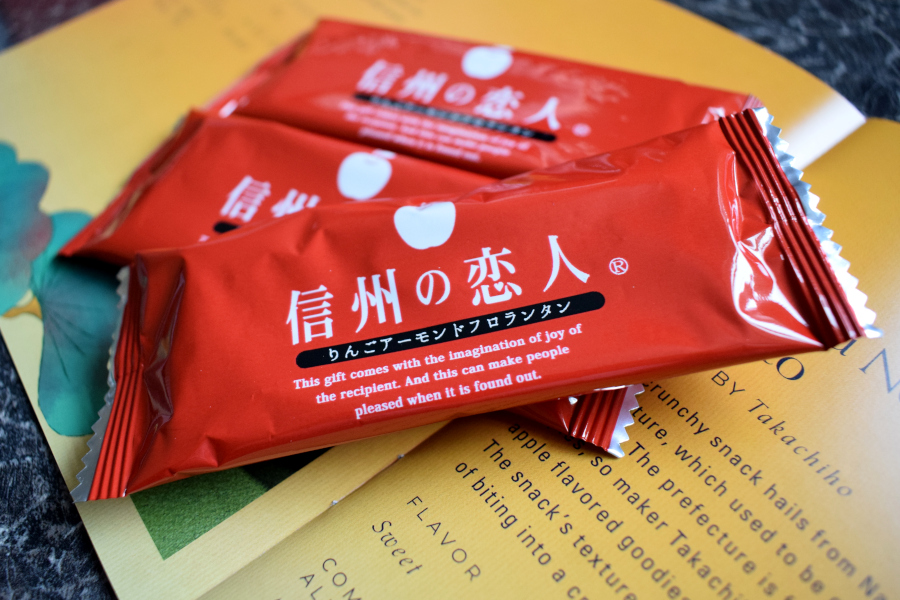 three individually wrapped apple and caramel crisp treats next to a leaflet describing them