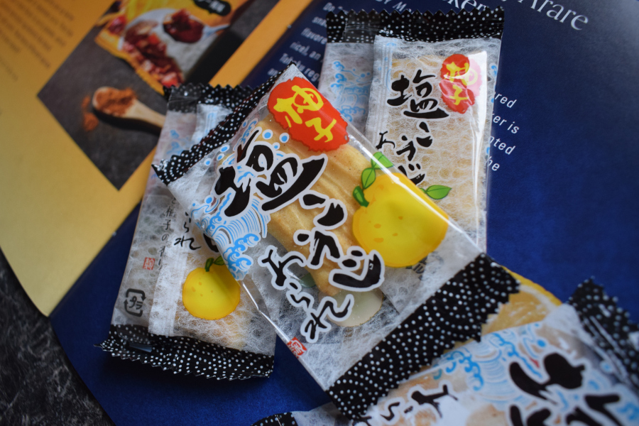 three individually wrapped yuzu salt crackers next to a leaflet describing them